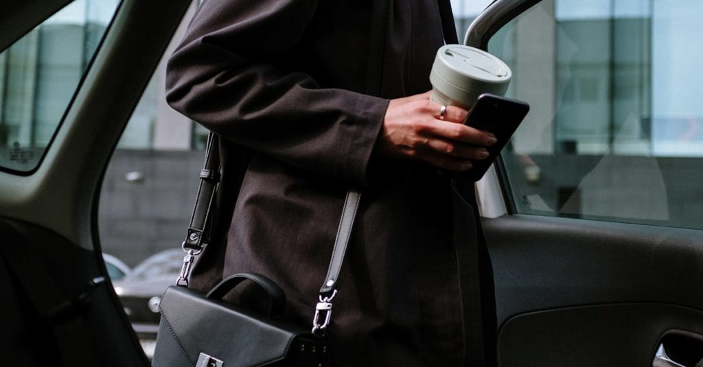 Stylish woman entering a car, holding coffee and smartphone, showcasing urban lifestyle.